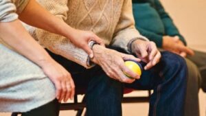 The hands of a caregiver and a senior preparing to throw a ball for a therapy dog