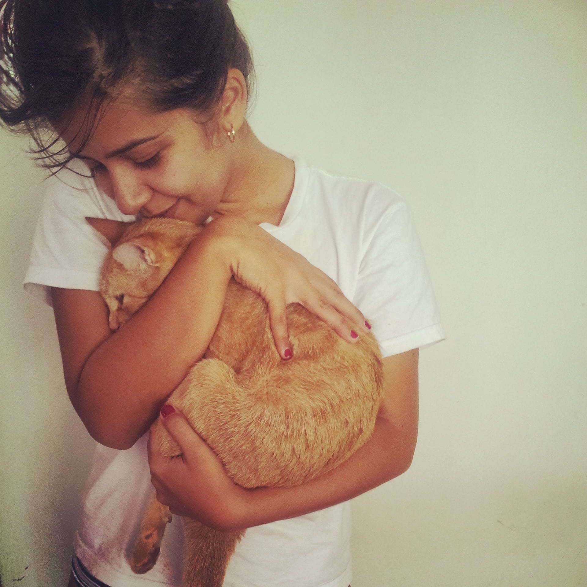 A tween girl holding and cuddling an orange tabby cat