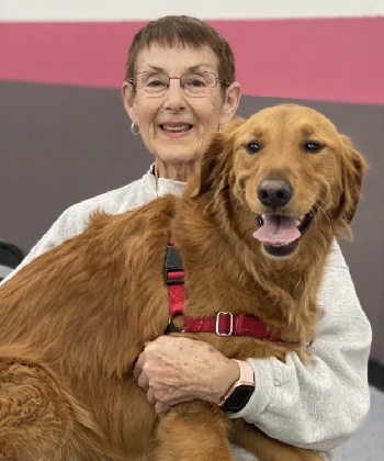 A smiling woman holding a happy golden retriever