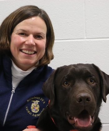 A smiling woman and a happy chocolate Labrador retriever