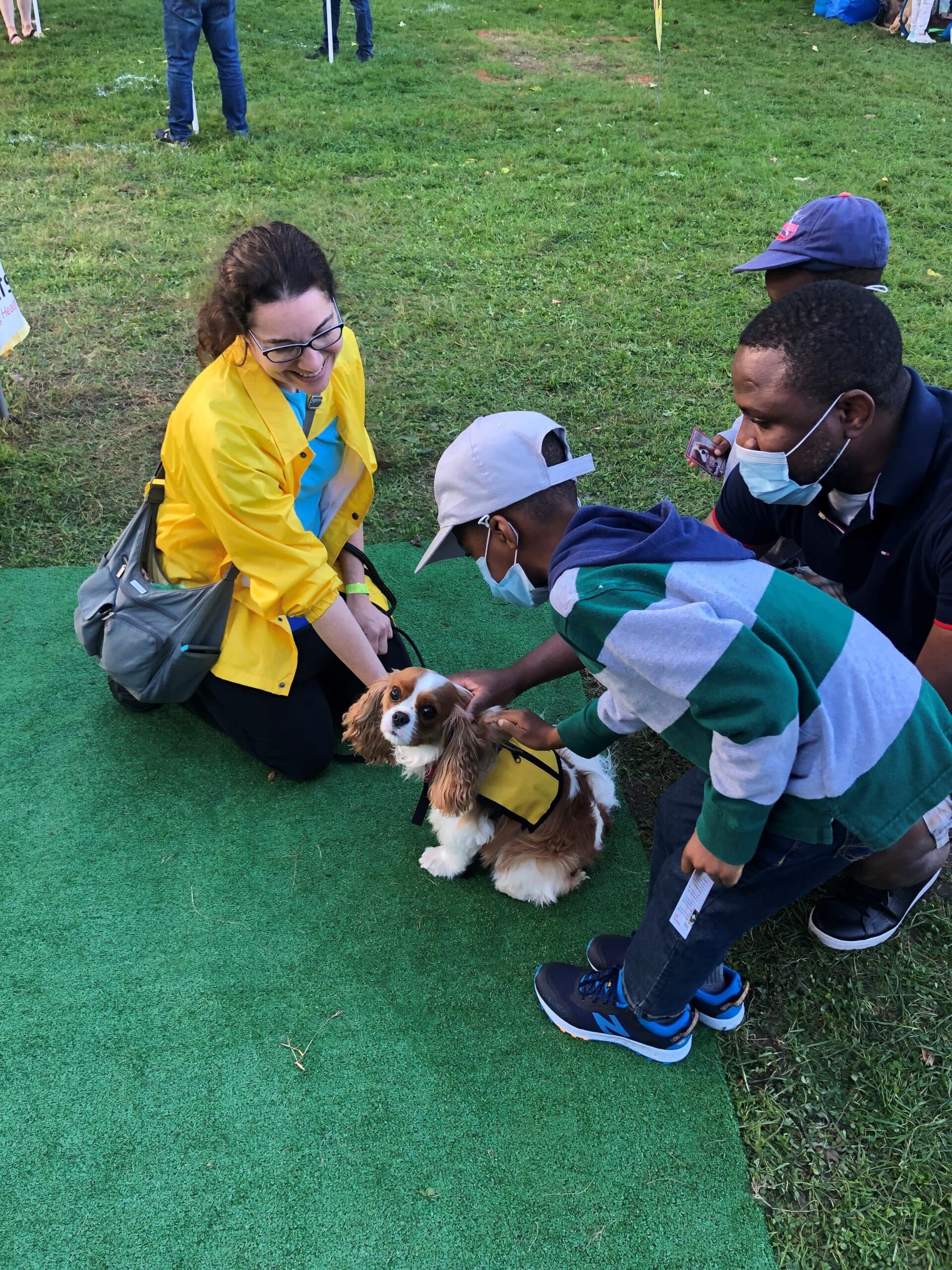 A therapy dog handler encourages two young boys and their father to pet her cavalier King Charles spaniel therapy dog.