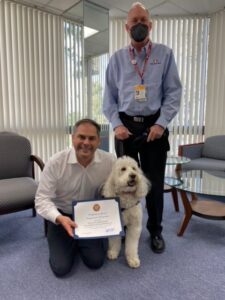 A white goldendoodle therapy dog and her handler with U.S. Representative Mike Garcia.