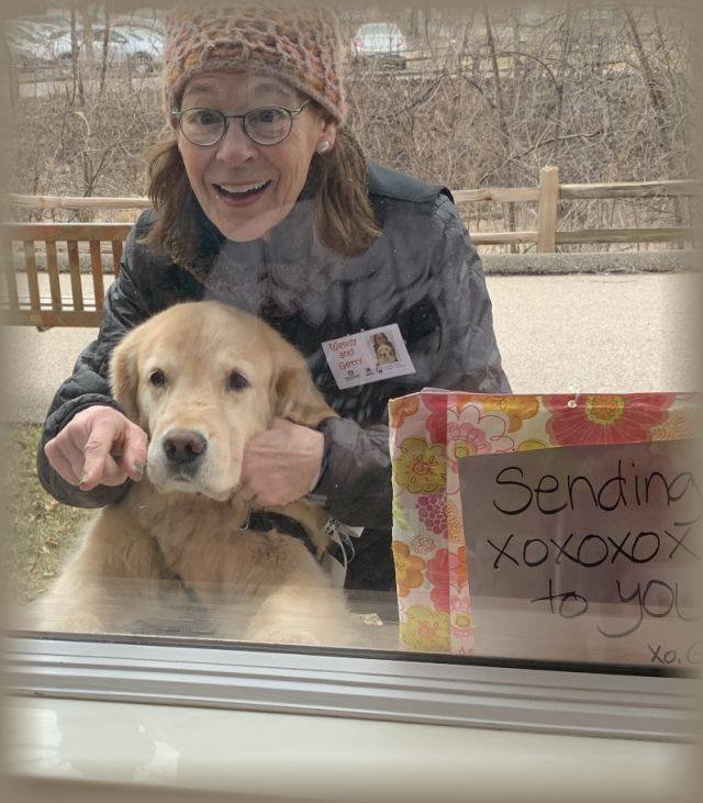 A therapy animal team makes a visit through the window of a facility