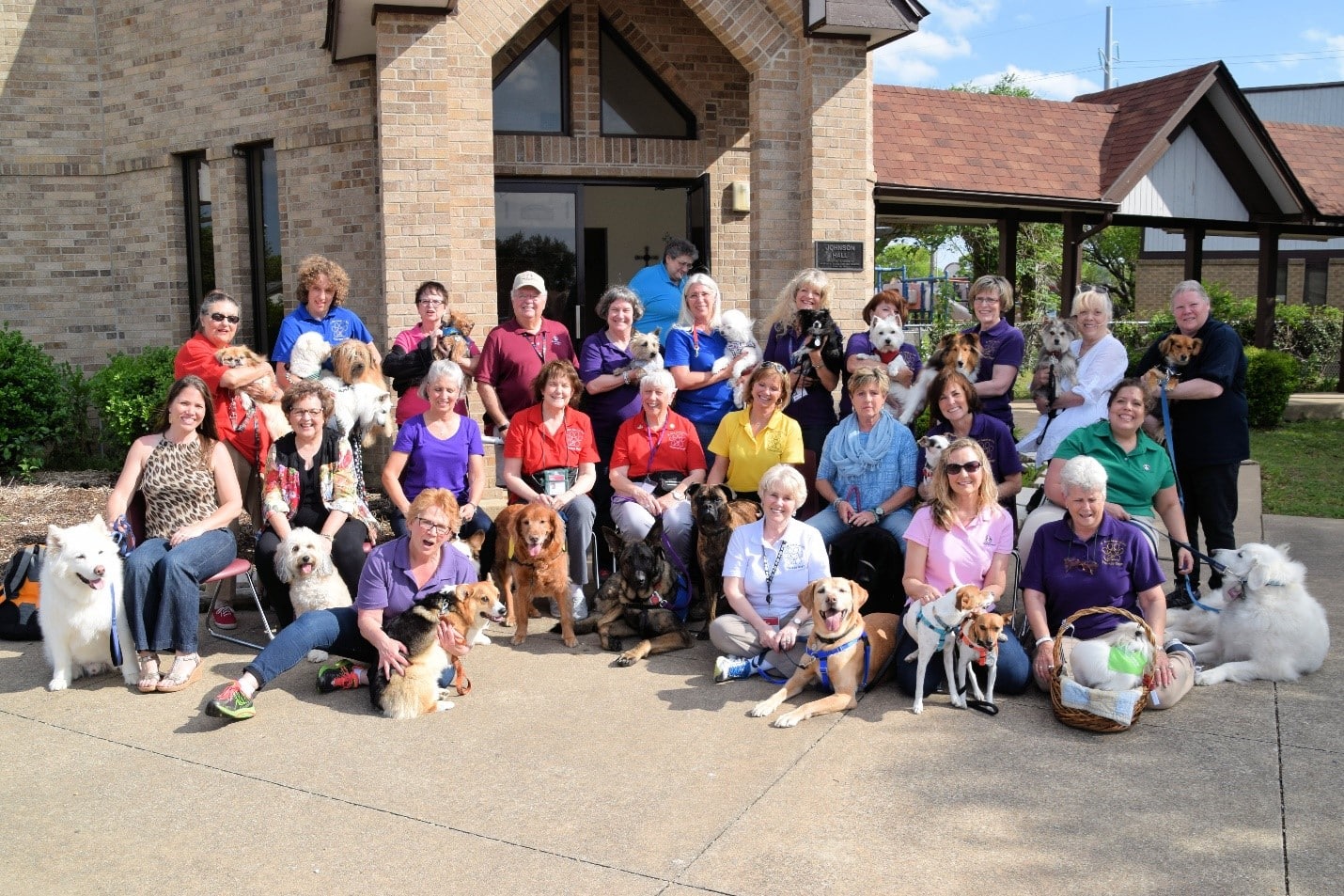 A large group of people poses with a variety of pets after a fundraising walk.
