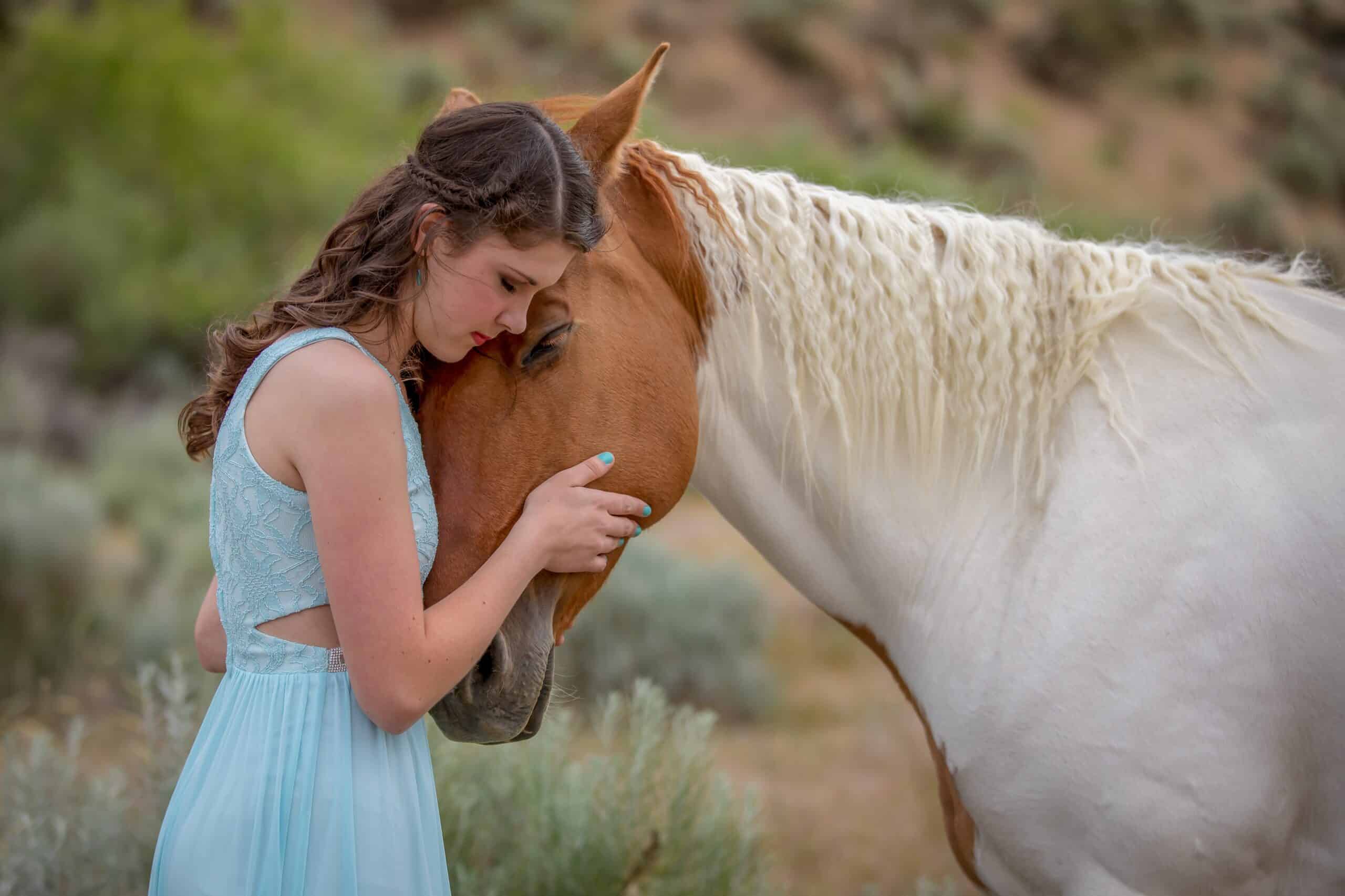 A young brown-haired woman, Kathryn Ribbens, embraces her brown and white horse. Photo provided by Kathryn Ribbens.