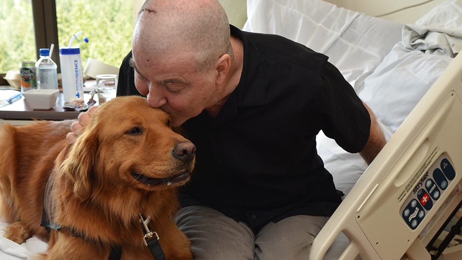 Hospital patient kisses a therapy dog during a visit.