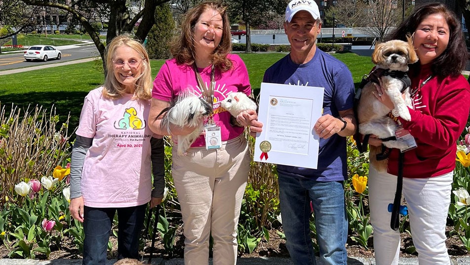 A group of therapy animal handlers pose with their National Therapy Animal Day proclamation.