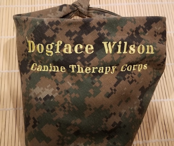 A dog scarf with a digital camo pattern and embroidery reading 