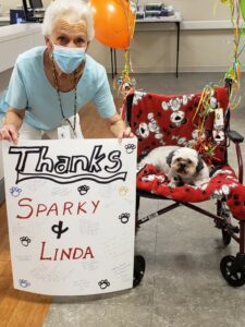 Lisa Anderson and therapy dog Sparky post with a sign thanking them for their work.