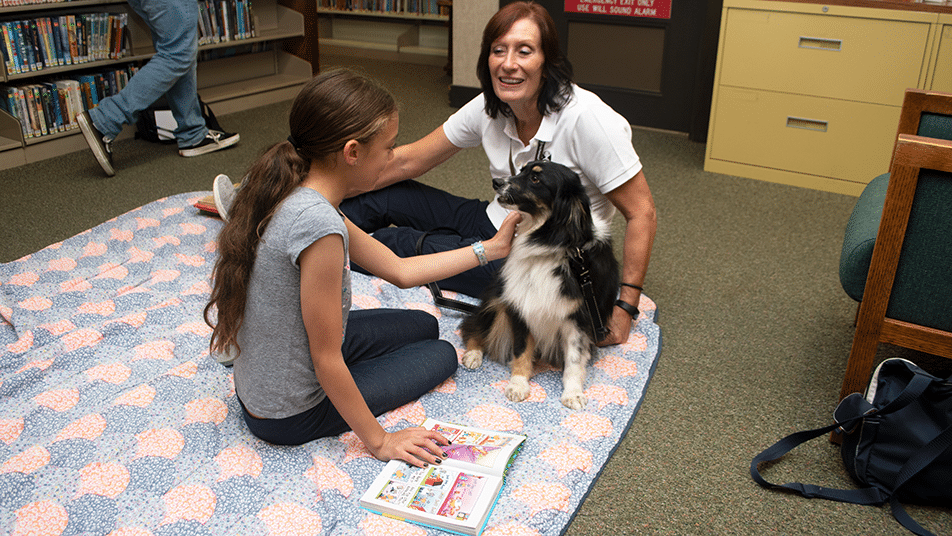 A therapy dog team during a reading visit with a young student.