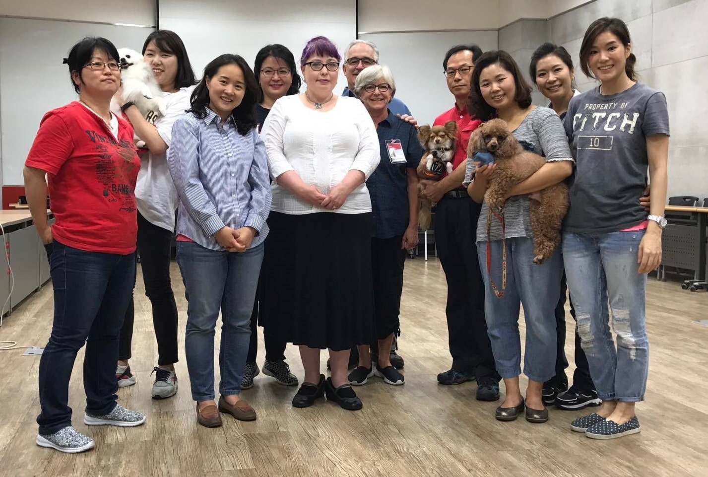 A group of people, some holding dogs, pose for a photo. Most of the people are Korean; three are caucasian.