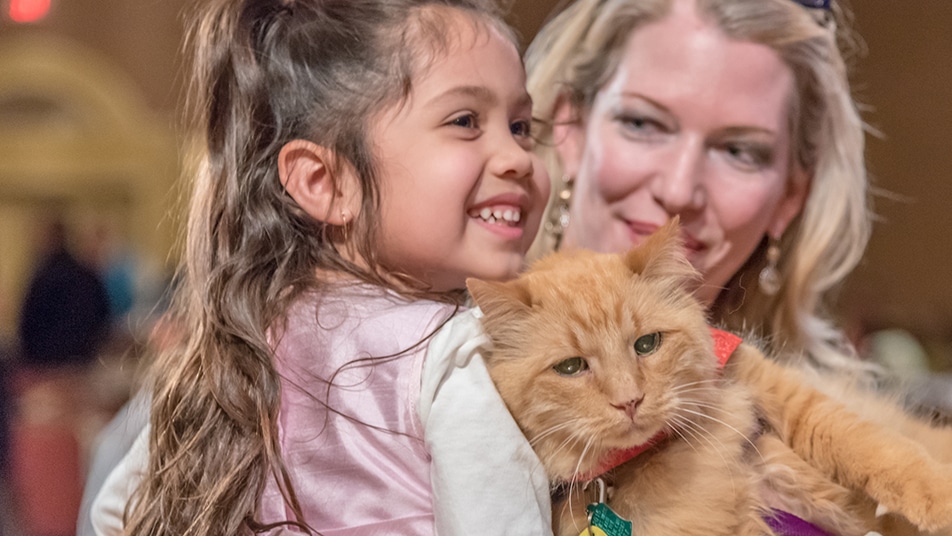 A girl and a woman with a therapy cat, smiling